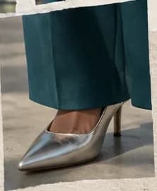 Scarpin prata metalizado, sob a barra de uma calça verde-petróleo